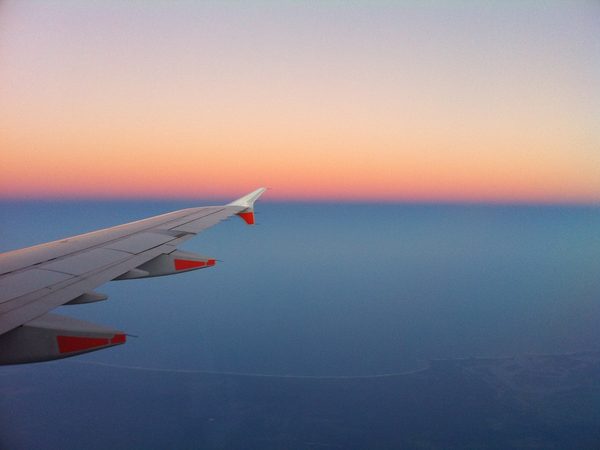夕焼けの空を飛ぶ飛行機の翼
